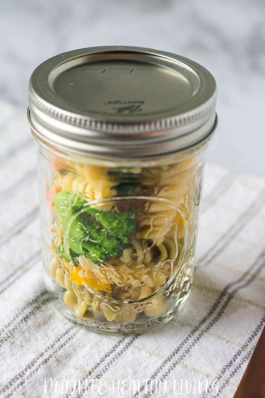 Featured image showing the finished pasta primavera salad in a jar ready to take for lunch!