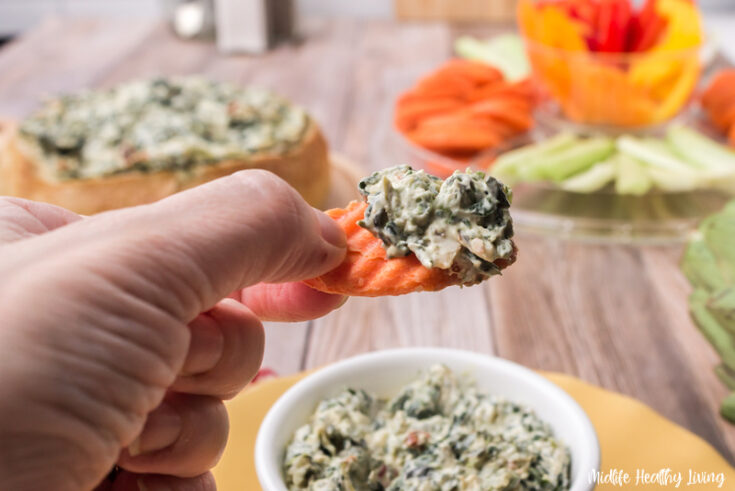 featured image showing the finished spinach dip on a carrot.