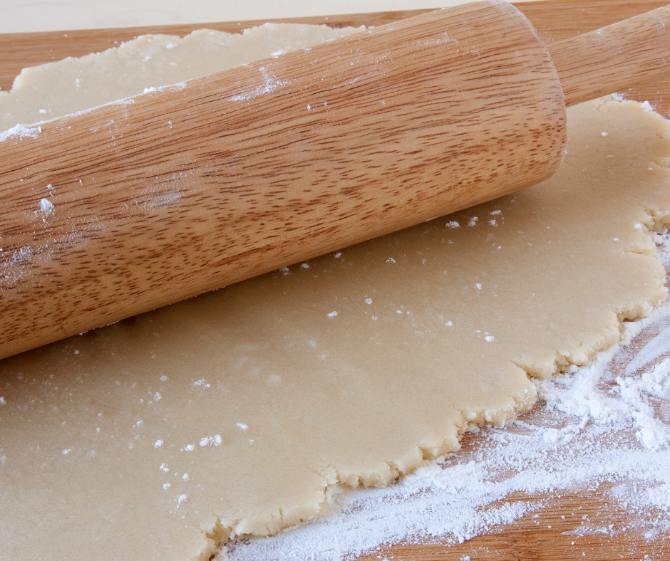 dough being rolled out on a floured counter. 