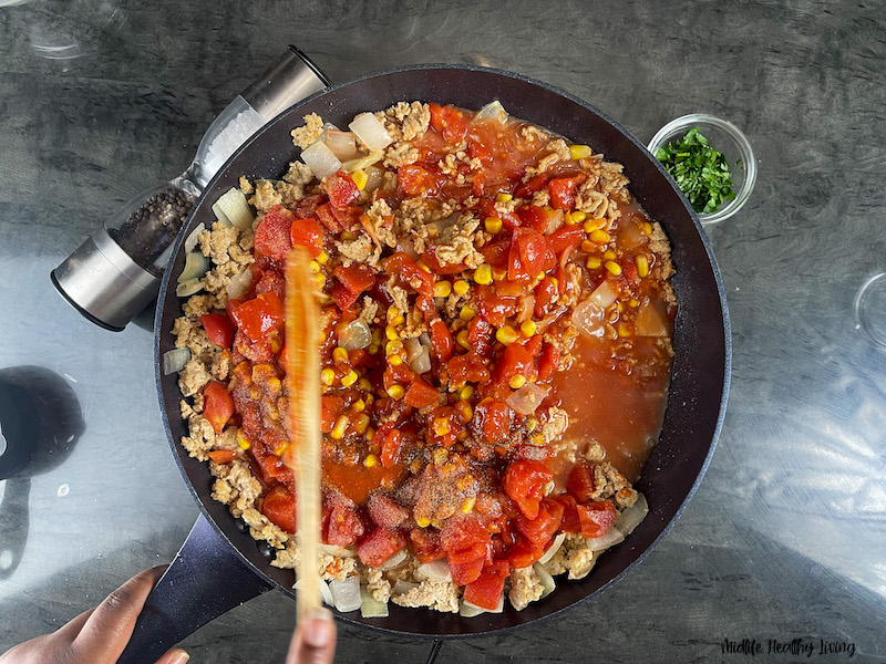 tomatoes being added to the cooking meat. 