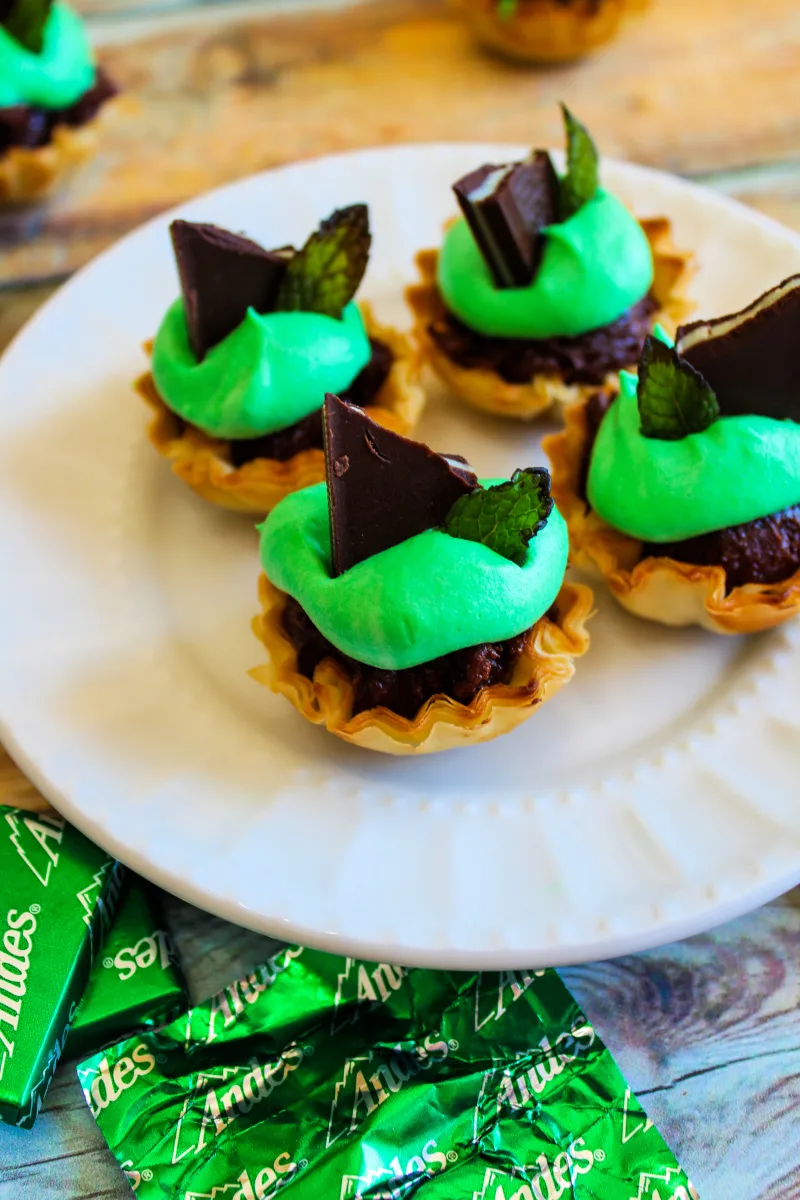 brownies in phyllo cups with green whipped topping on a white plate