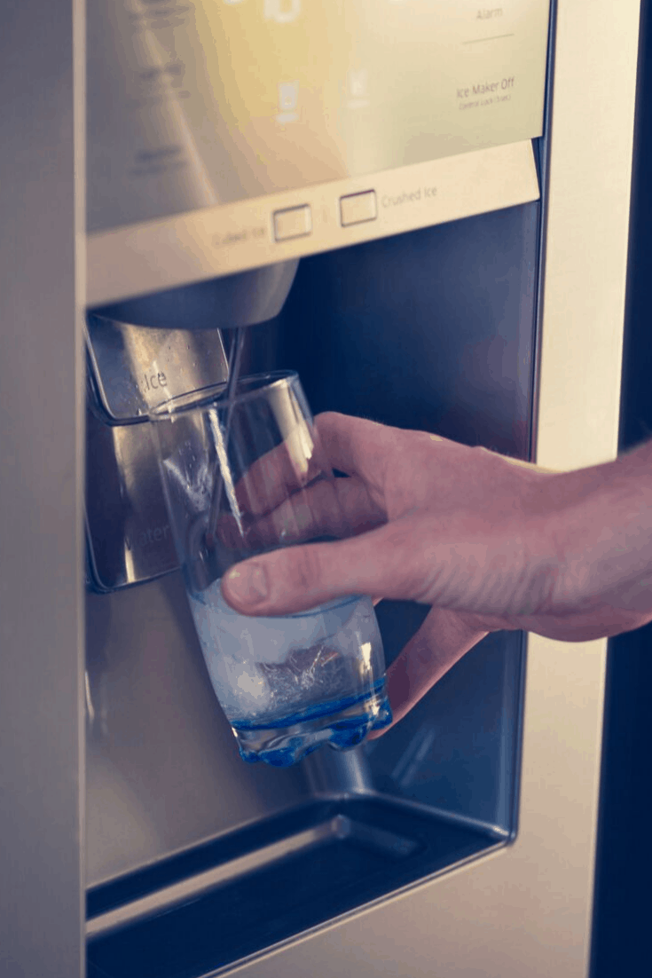 Water dispensing into a glass from a refrigerator. 