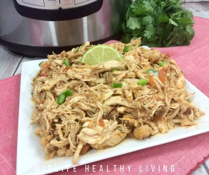 Mexican shredded chicken topped with lime served on a white plate.