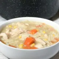 soup in a white bowl in front of the cooking pot