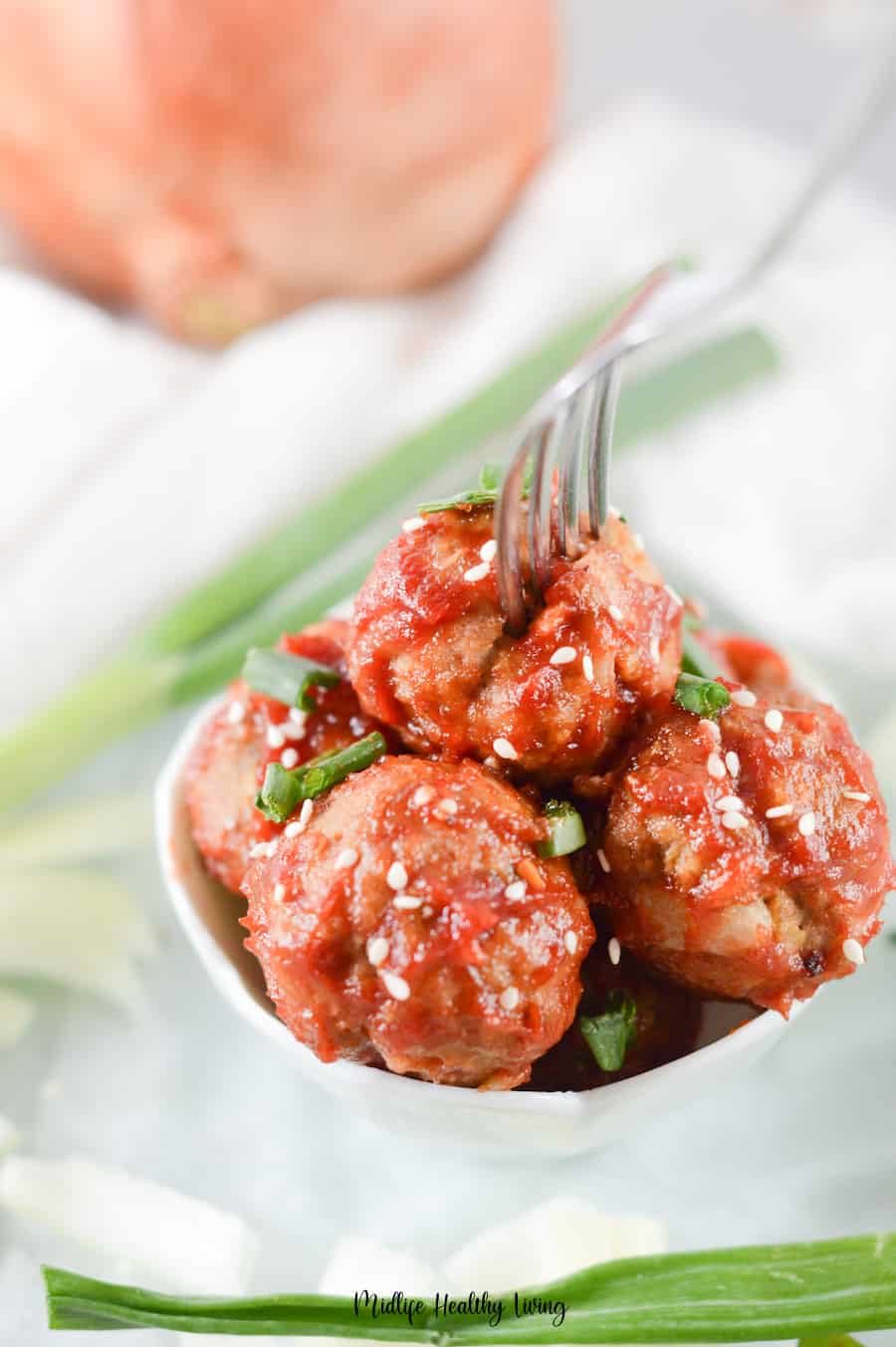 A top down look at the bowl full of finished sweet and spicy meatballs. 
