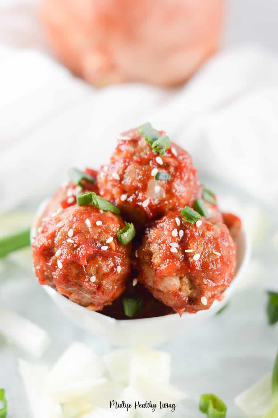 A close up look at the finished meatballs with sesame seeds and scallions on top. 