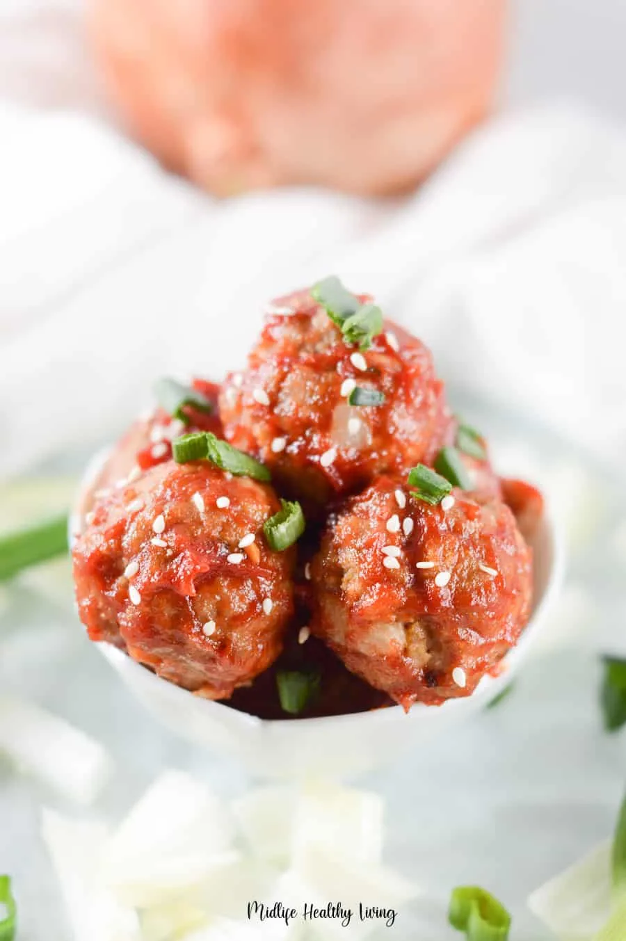 A close up look at the finished meatballs with sesame seeds and scallions on top. 