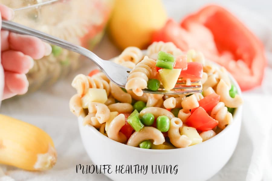 A fork full of the finished pasta salad is held up to the camera so we can see all the veggies and pasta! 