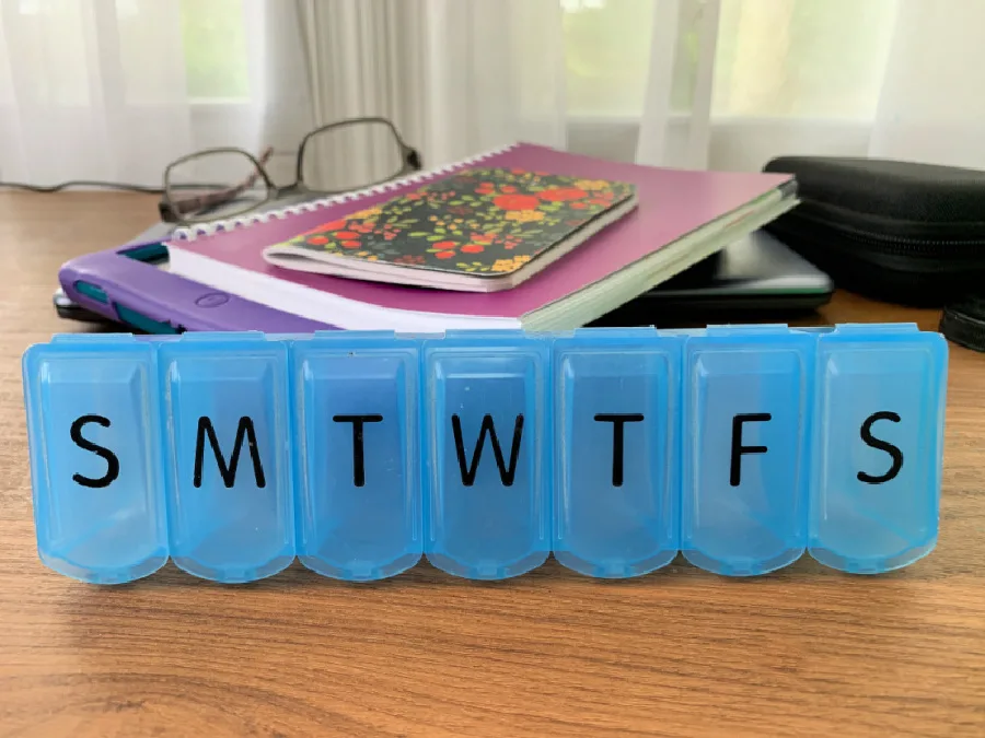 blue pill organizing box with the letters of the days of week on each compartment