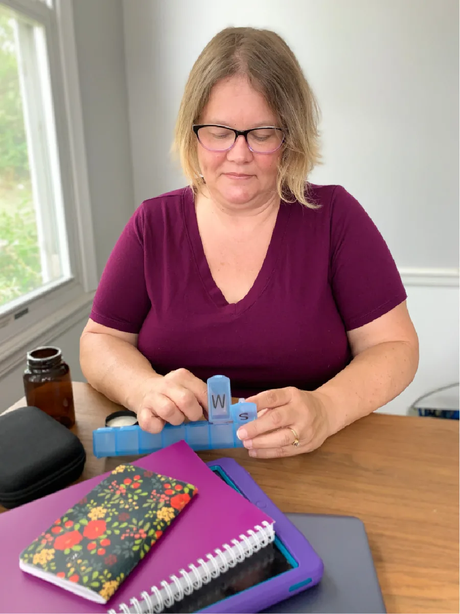 Caucasion middle age female sorting medications into a blue pill organizer