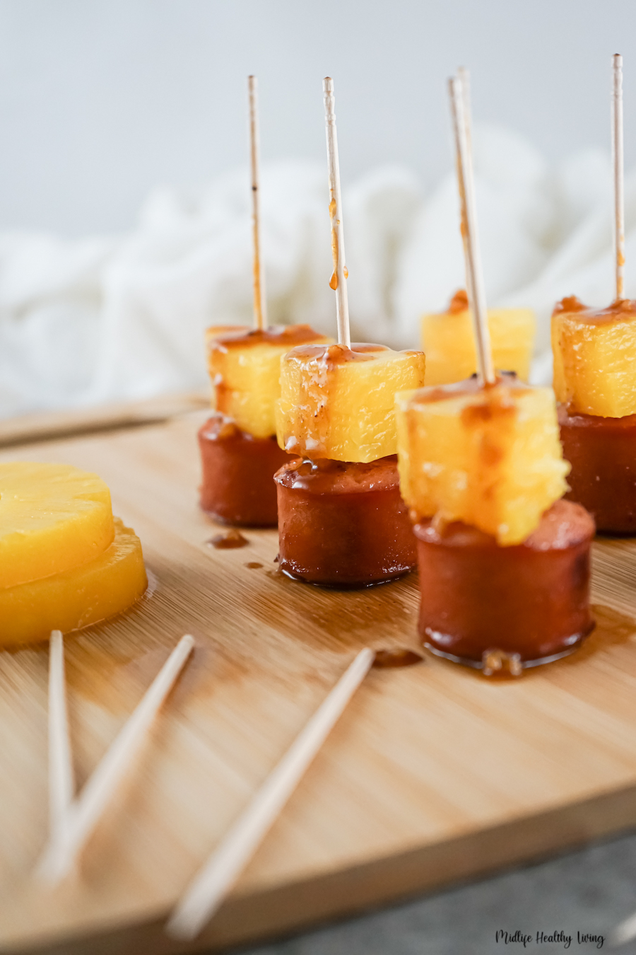 Sausage pineapple bites ready to eat on a cutting board. 