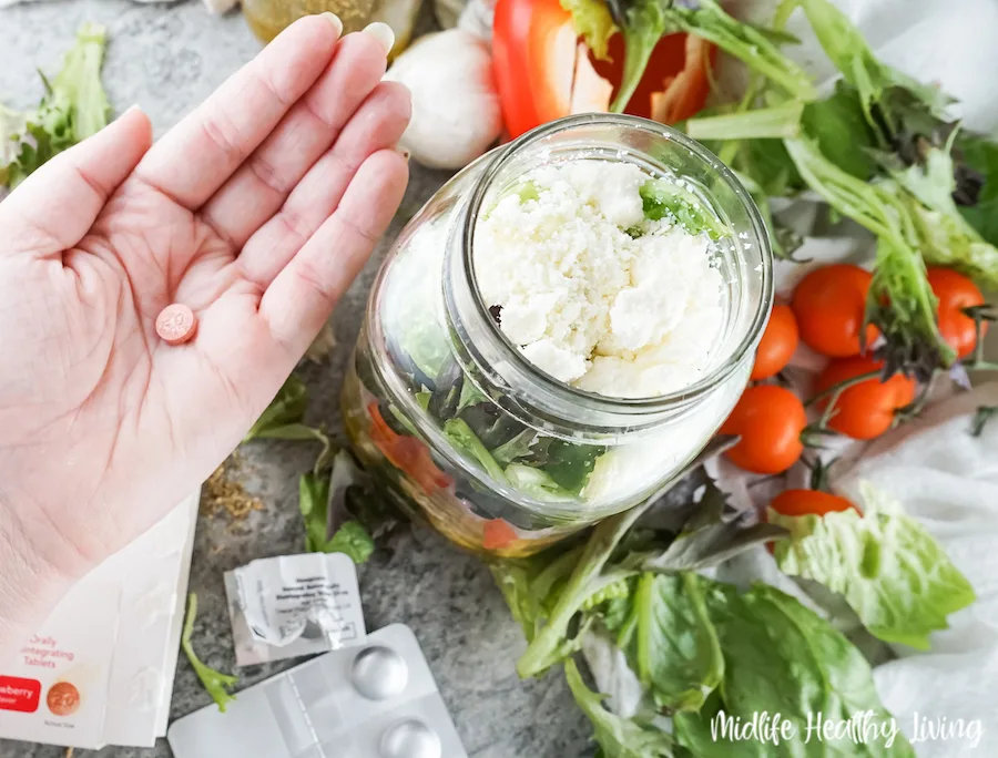 A look at the small omeprazole tablet in hand next to the jar salad. 