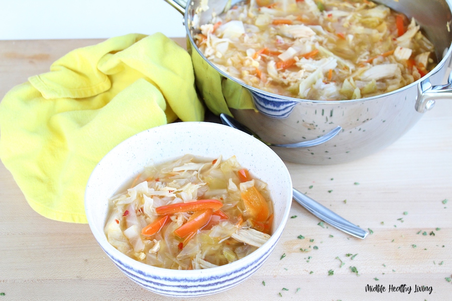 A bowl of soup in front of the pot of soup ready to be shared. 