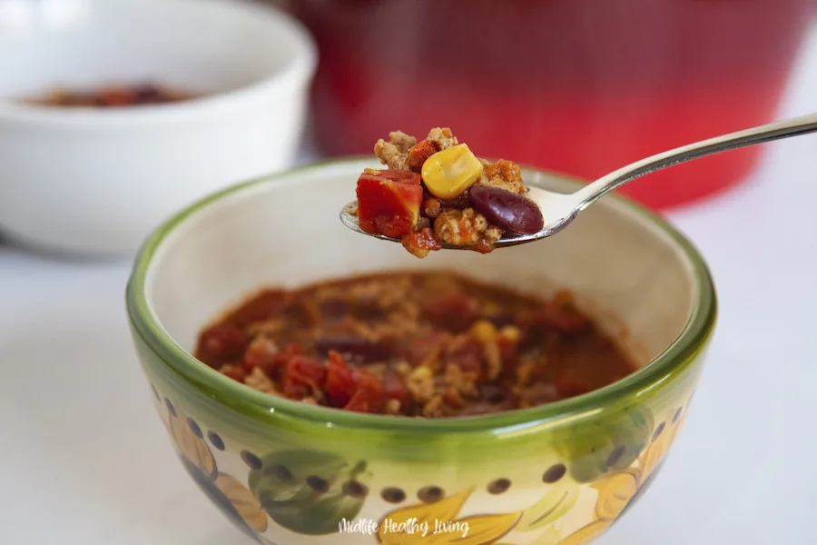 A spoon full of chili held up to show all the delicious ingredients. 
