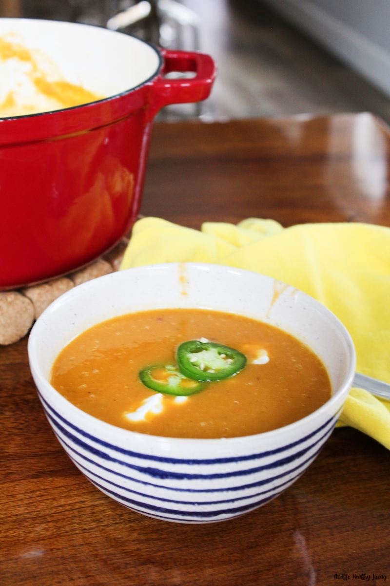 A view of the bowl of finished weight watchers pumpkin soup with pot in the background ready to serve. 