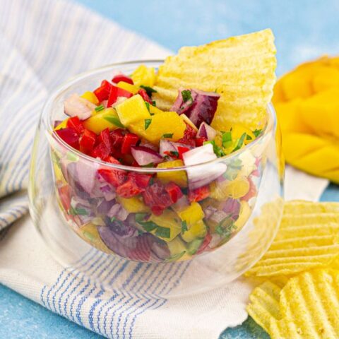 Mango Habanero Salsa in a glass bowl with a chip