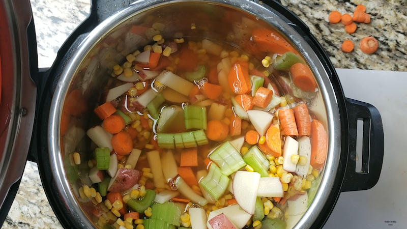 broth and seasonings being added to the instant pot corn soup. 