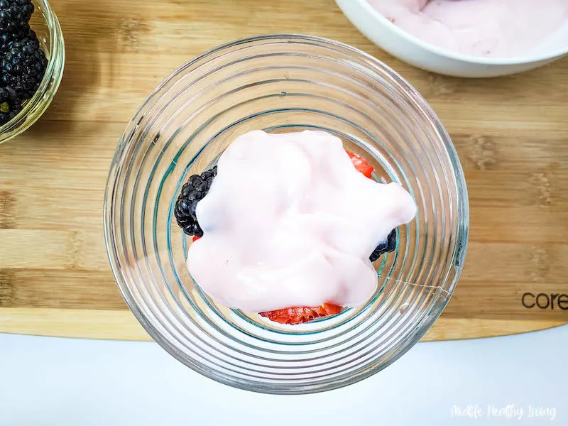 another layer of yogurt being added on top of the fruit. 