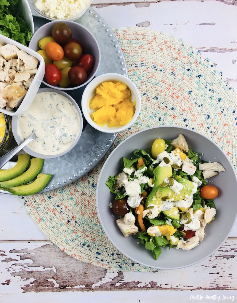 Salad prepared and ready to be served with ingredients on a plate in the background. 