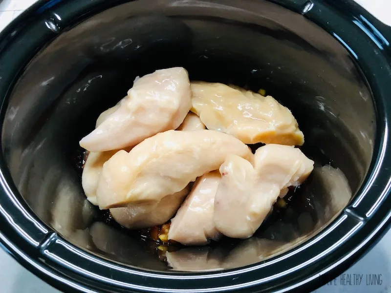 Chicken placed on top of initial layer of salsa in the crockpot. 