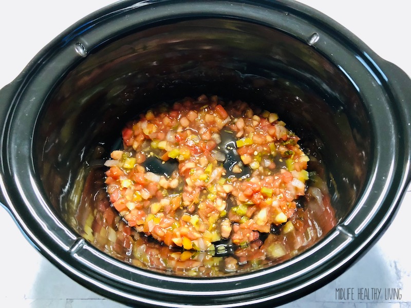 Some salsa on the bottom of the slow cooker. 