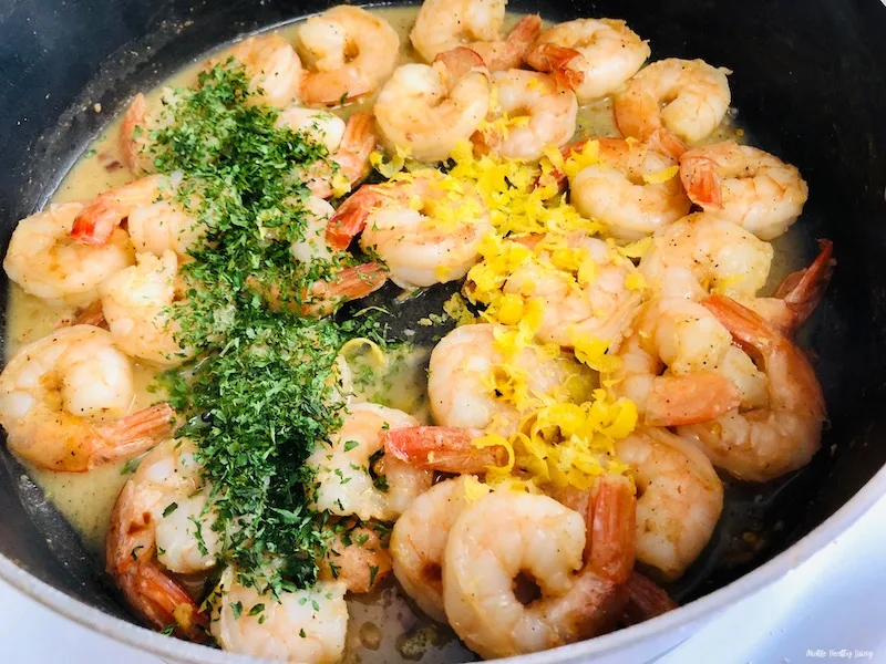 Parsley and lemon zest being added to the finished shrimp.