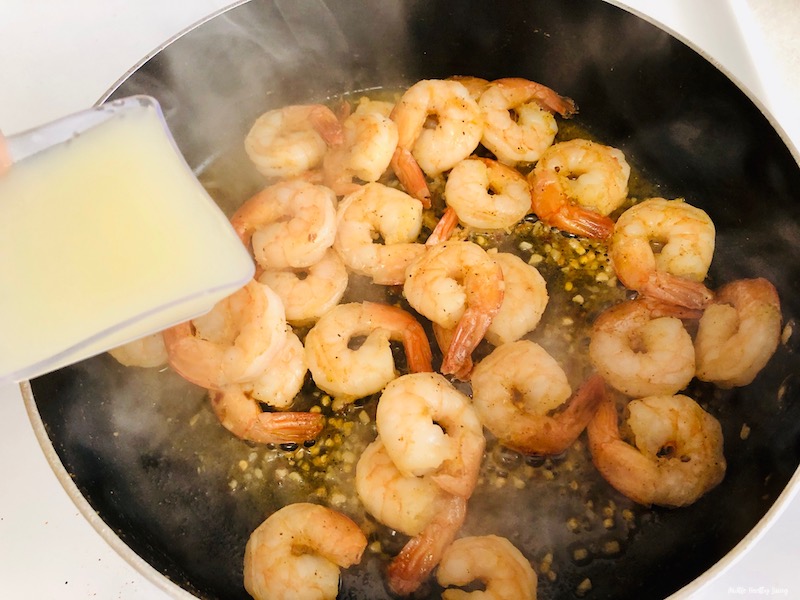lemon juice being added to the cooking shrimp and seasoning. 