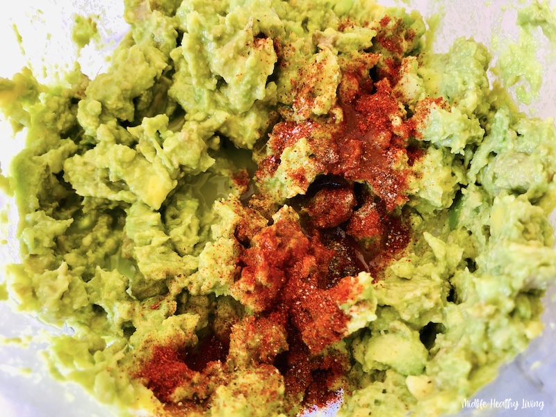 seasoning being added to the mashed avocado. 