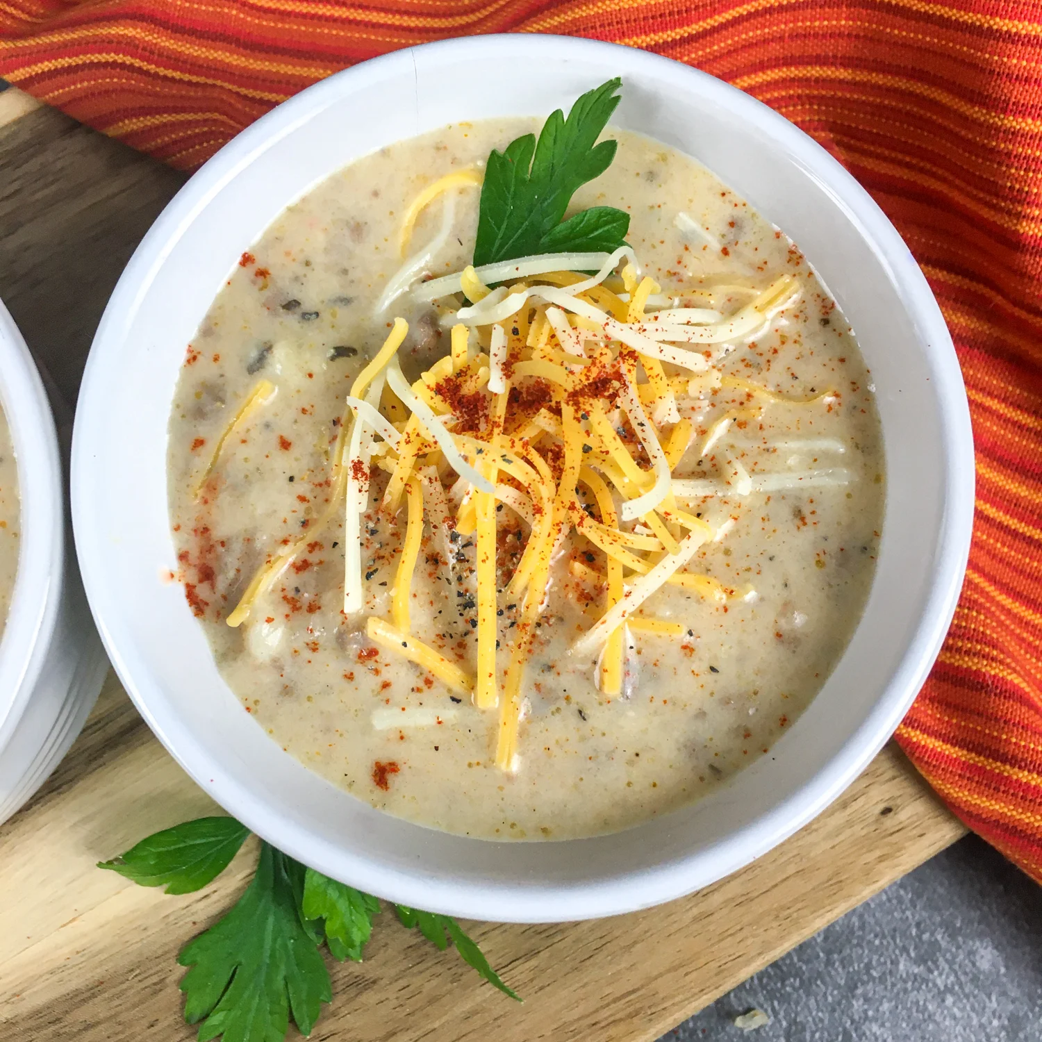 white bowl containing cheeseburger soup topped with grated cheddar cheese