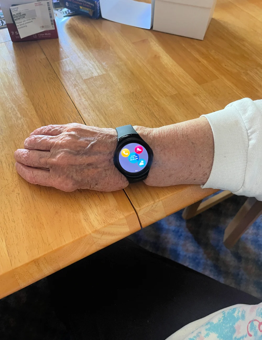 sos smartwatch on the arm of elderly person. Arm is on table. for post what to do when your parents are aging