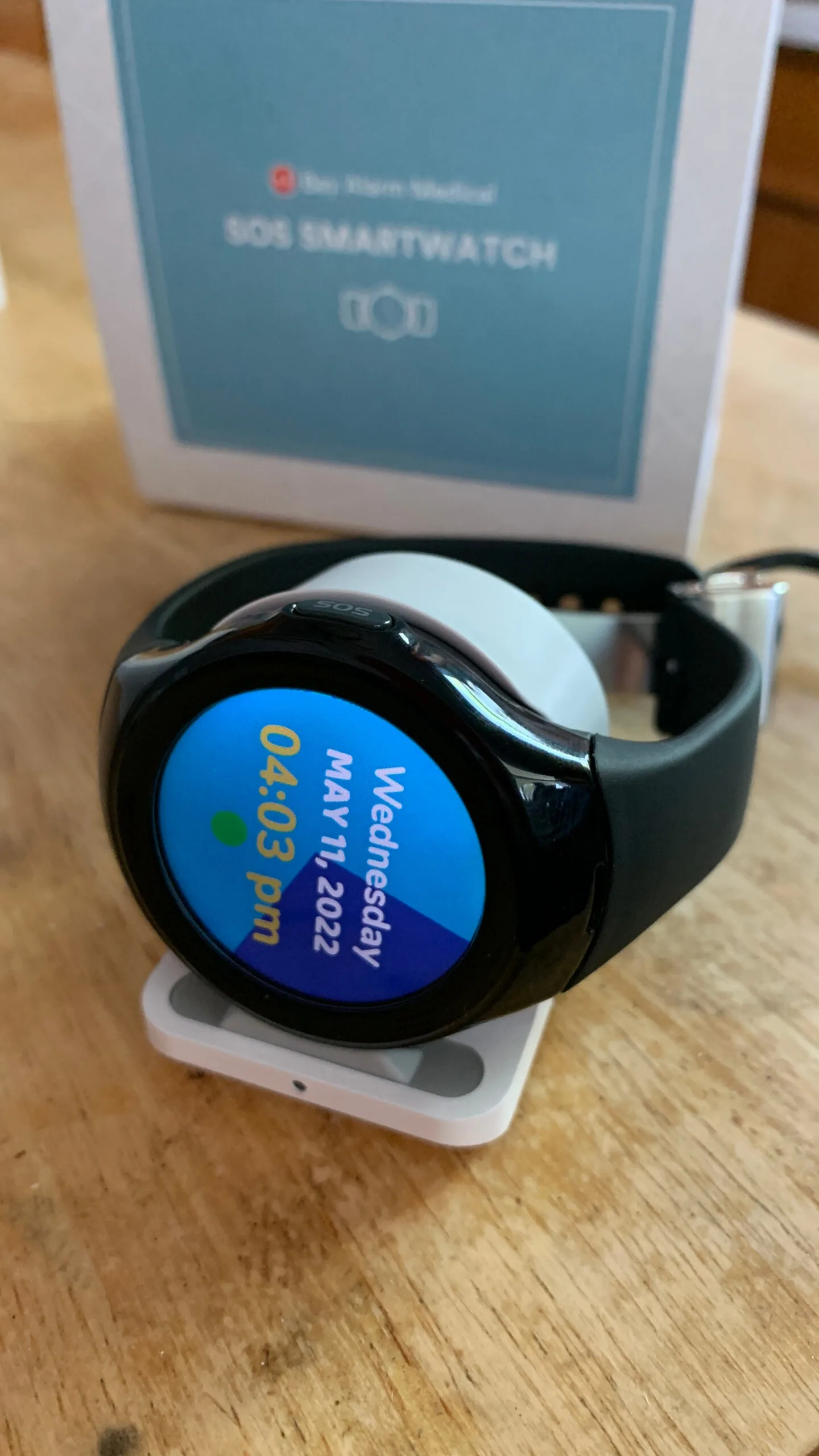 SOS smart watch resting on its charging port.