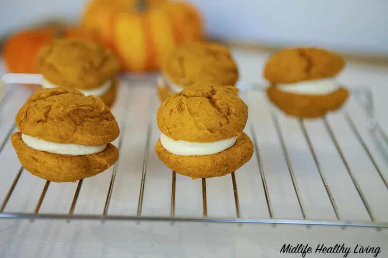 Finished pumpkin whoopie pies on a cooling rack ready to eat