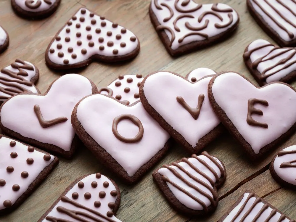 Chocolate heart shaped cookies with pink frosting. Each cookie has a letter to spell out "LOVE"