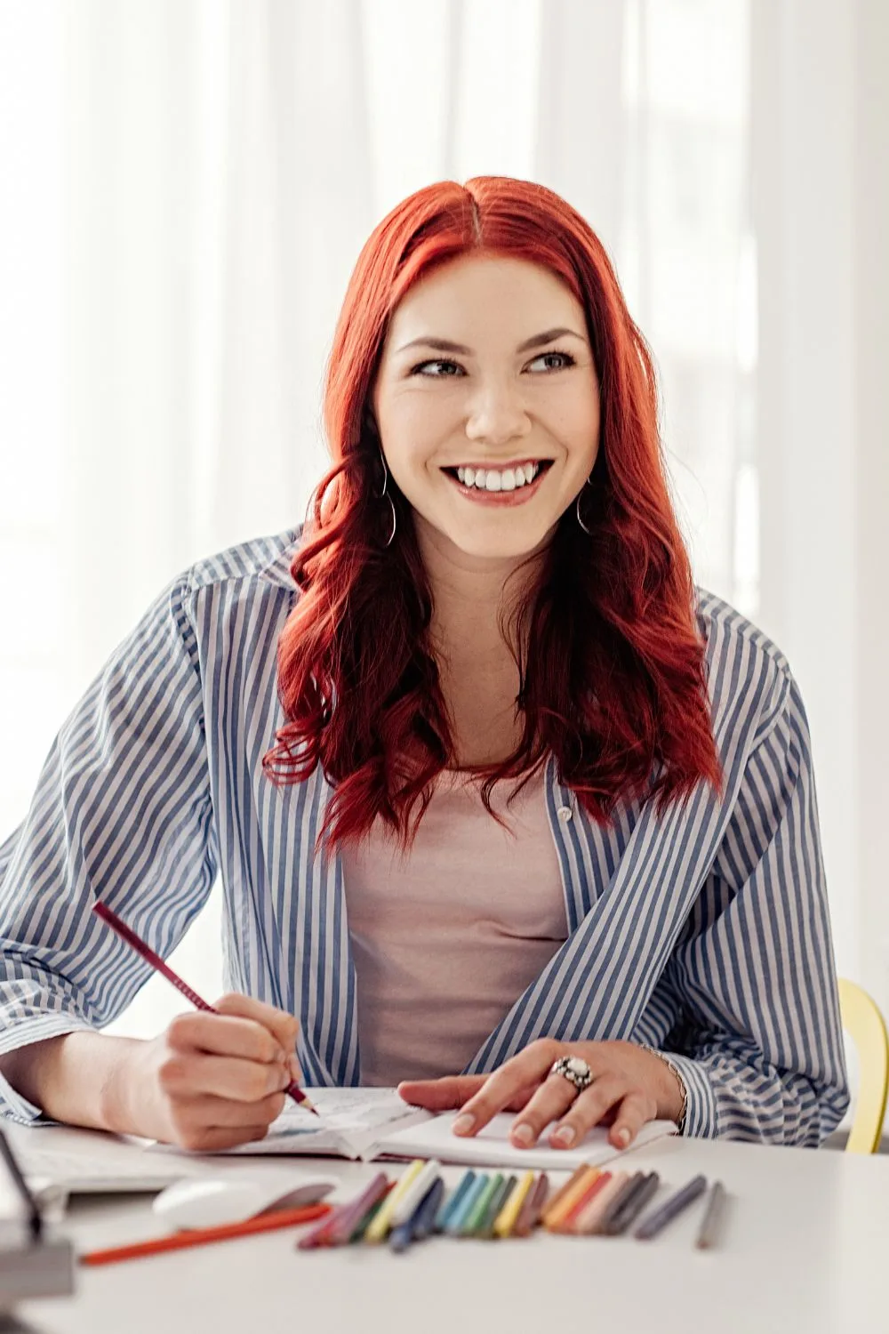 Woman sitting at a table with colored pencils