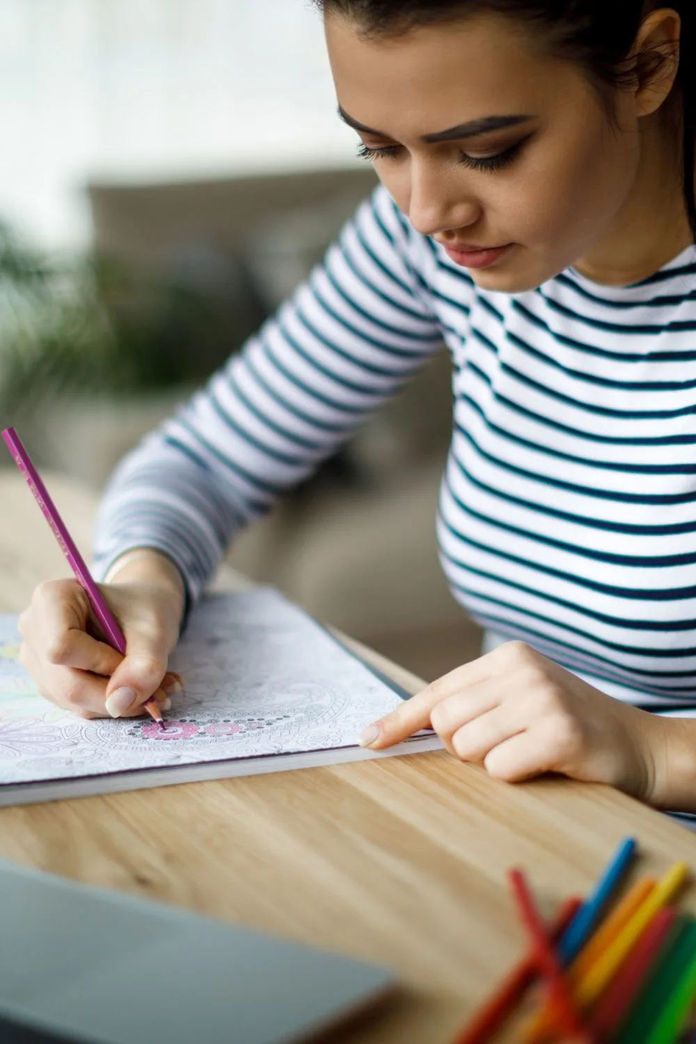 Woman sitting at a table coloring with colored pencils