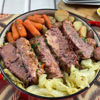 Completed corned beef surrounded by carrots, onions, potatoes and cabbage