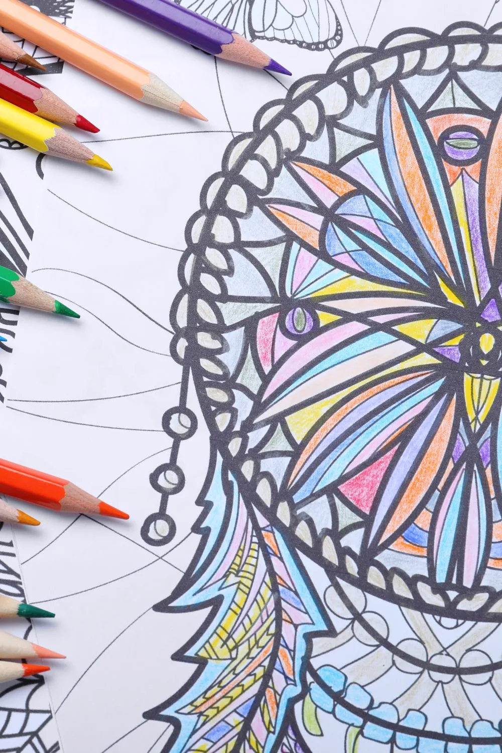 a coloring page of a dream catcher that has been colored in by the surrounding pencil crayons