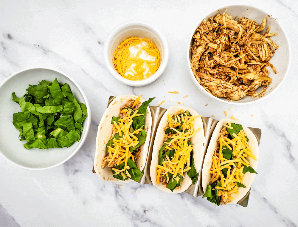 cheddar cheese on top of chicken and lettuce on taco shell for healthy street tacos