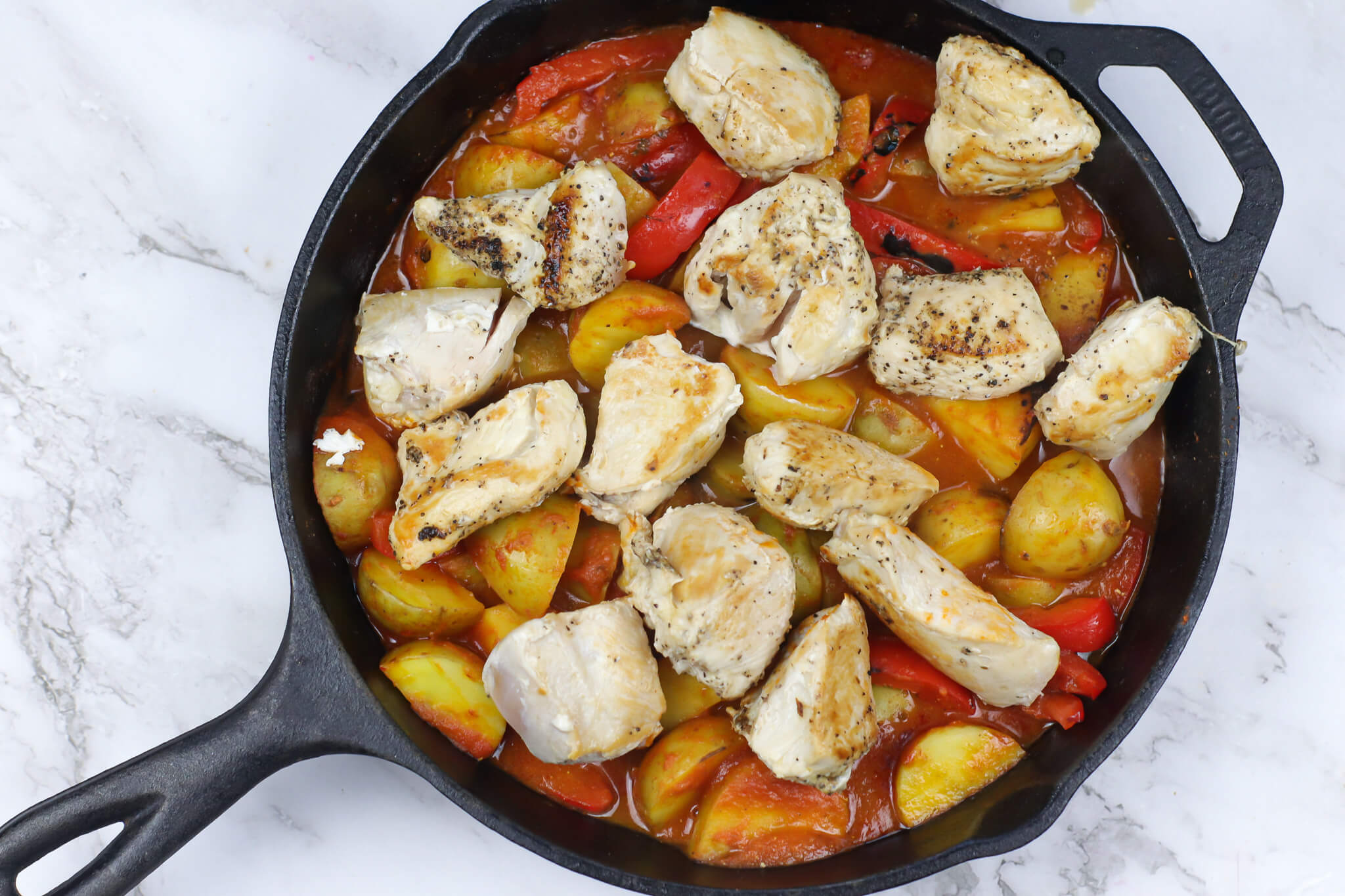 cooked chicken with potatoes and peppers in a skillet