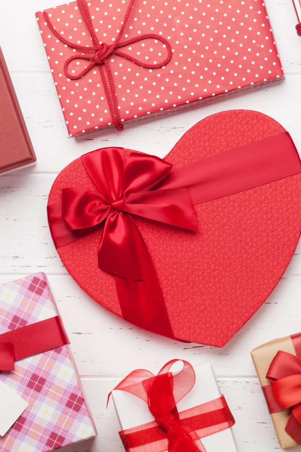 A flat lay of wrapped gifts in pinks and reds.
