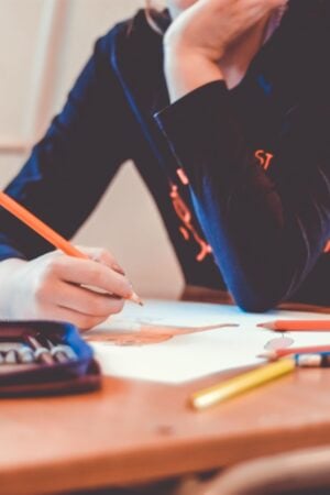 a person sitting at a table coloring with pencil crayons