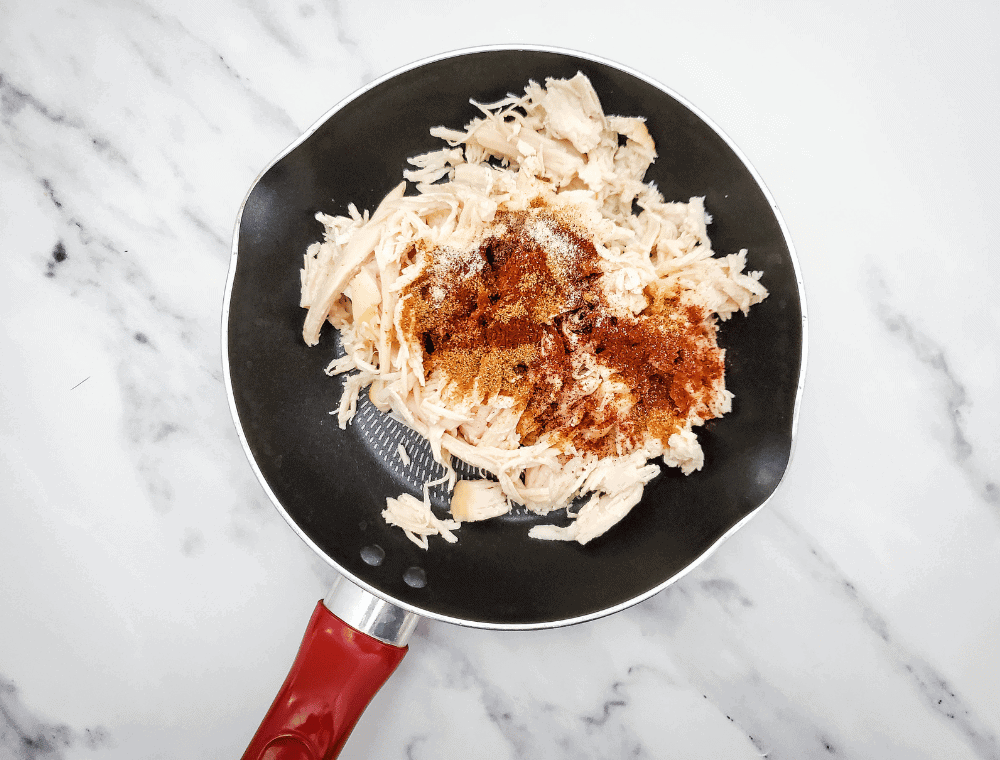 cooking shredded chicken with taco spices for street taco