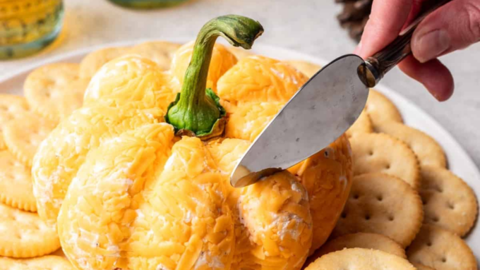 A pumpkin shaped cheese ball with crackers.