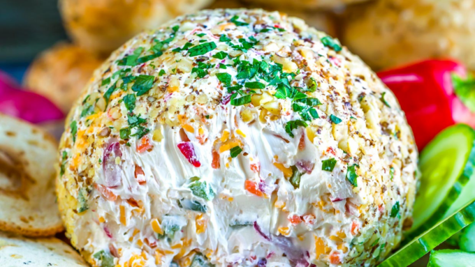 A veggie and cream cheese ball with veggies and crackers.