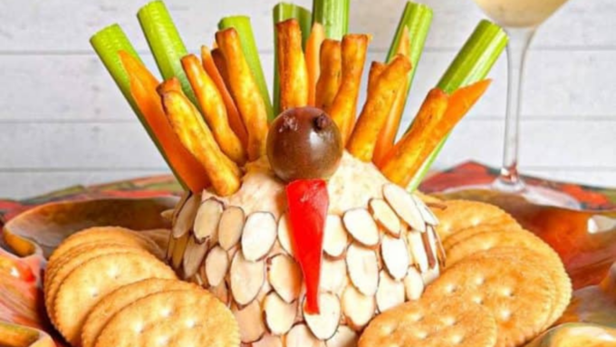 A cheese ball with bread stick and celery feathers.