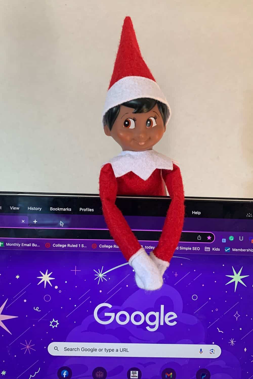 Elf on the Shelf hanging onto the back of a laptop computer