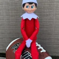 Elf on the Shelf sitting on a football