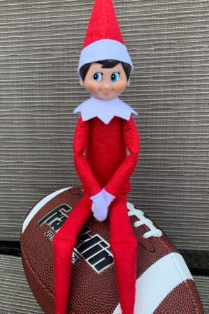Elf on the Shelf sitting on a football