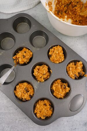 scooping batter into a muffin tin