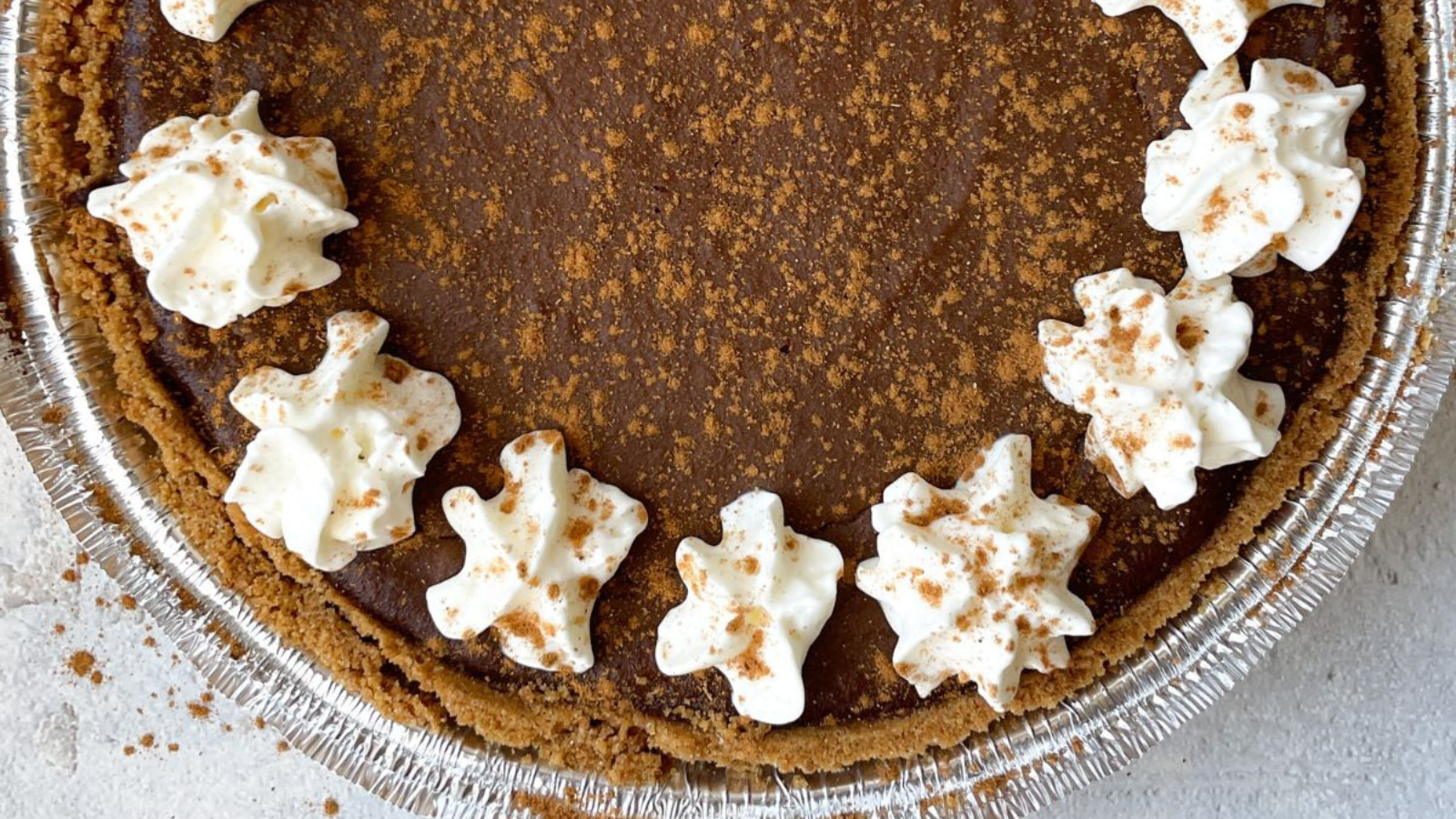 A chocolate pumpkin pie with whipped cream.
